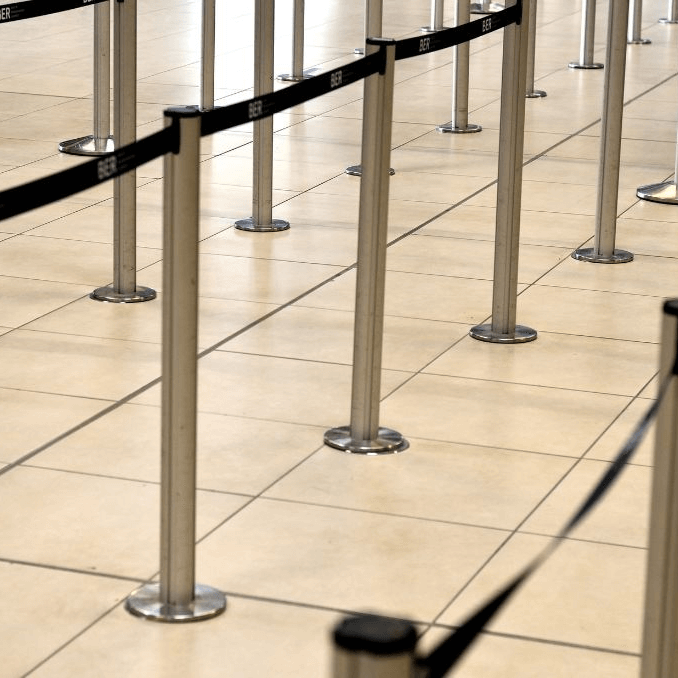 Queue management system with stanchions and black retractable belts on a tiled floor.